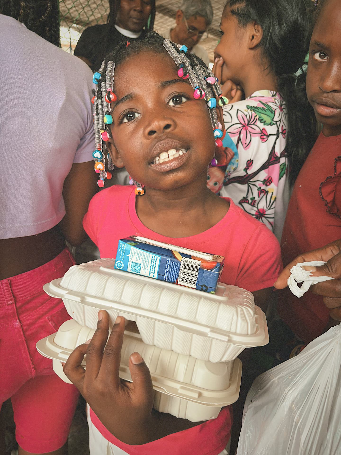 Niña sonriendo con su almuerzo en las manos